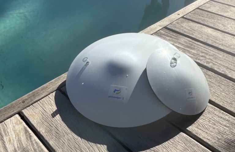 Deux objets en forme de dôme blancs pour mise en dépression de canalisation posés sur une terrasse en bois près d'une piscine.