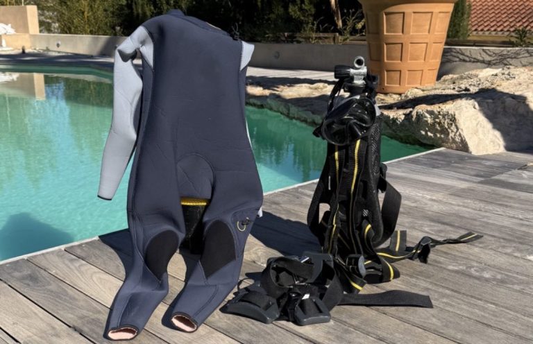 Équipements de plongée, y compris une combinaison et des bouteilles, près d'une piscine.