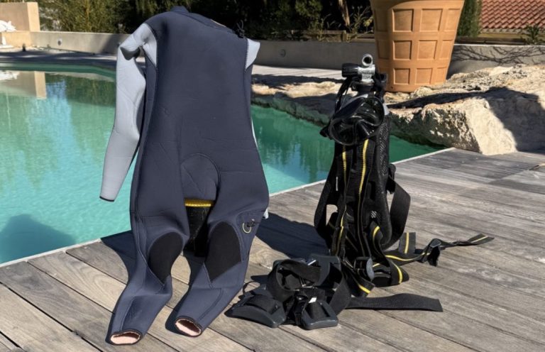 Équipements de plongée, y compris une combinaison et des bouteilles, près d'une piscine. 